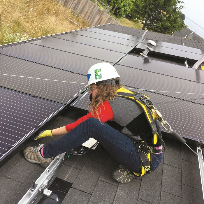 A GRID Alternatives volunteer helps install solar on a roof in Loleta, California.