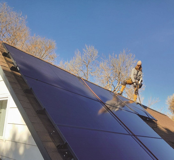 Riley Neugebauer, solar installer and apprentice at Namaste Solar, works on a residential solar project.