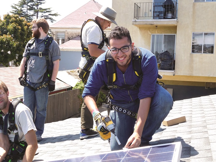 A solar ambassador installs renewable energy on a roof in Oakland, California.