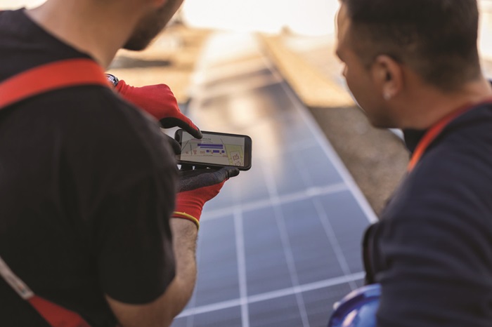 Using a smartphone allows two solar technicians to examine a diagram. (Credit: Jose Carlos Cerdeno)