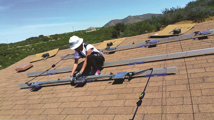 Solar installers work long hours on rooftops preparing supporting hardware and other components of renewable energy systems.
